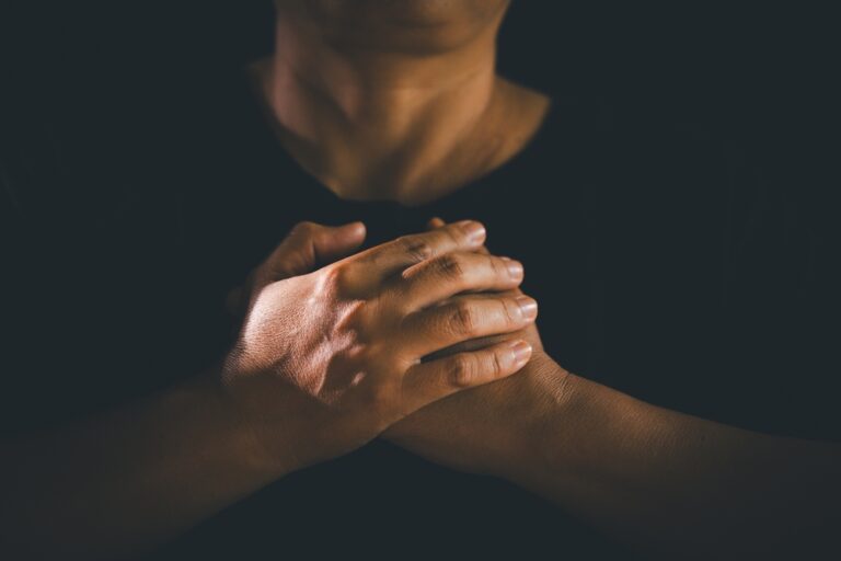 Hands,Clasped,In,Prayer,Over,The,Holy,Bible,,The,Faithful